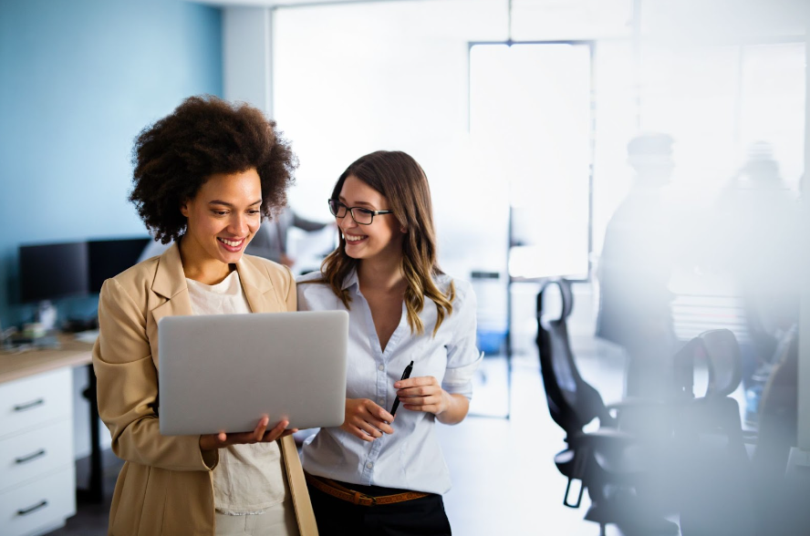 two-women-smiling-in-front-of-a-laptop
