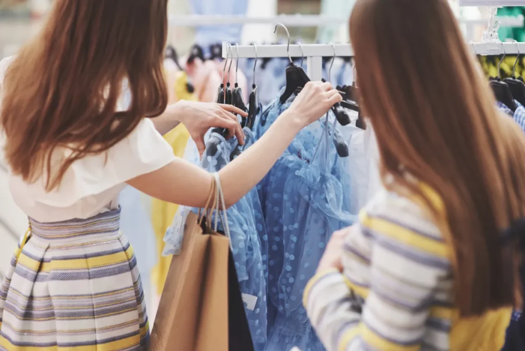 Two women shopping in a store, looking at clothing