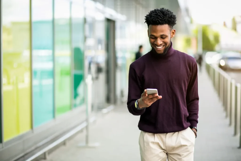 African Business Person on phone walking down street successful
