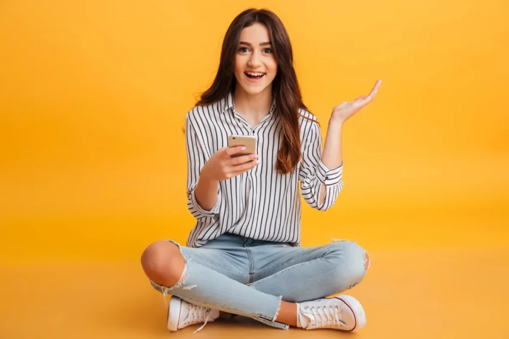 excited girl with yellow background and phone